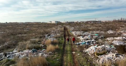 Two people walking on a huge aste, garbade, dump, rubbish landill in Bucharest Stock Footage 198212225