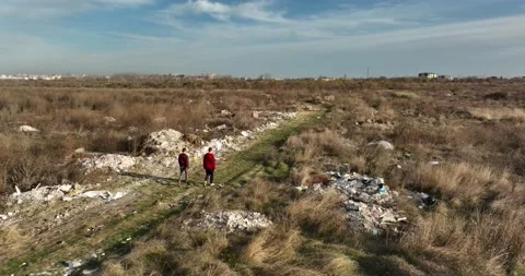 Two people walking on a huge aste, garbade, dump, rubbish landill in Bucharest Stock Footage 198212535