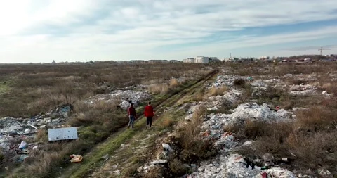 Two people walking on a huge aste, garbade, dump, rubbish landill in Bucharest Stock Footage 198212703