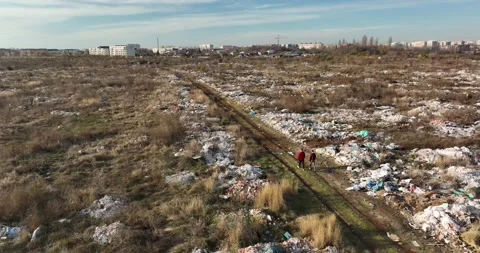 Two people walking on a huge aste, garbade, dump, rubbish landill in Bucharest Stock Footage 198212741