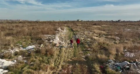 Two people walking on a huge aste, garbade, dump, rubbish landill in Bucharest Stock Footage 198212797