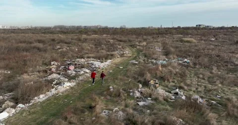 Two people walking on a huge aste, garbade, dump, rubbish landill in Bucharest Stock Footage 198212844