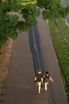 Two people walking on a path casting long shadows in the afternoon sun Stock-Fotos