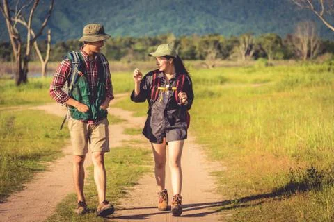 Two people walking on path in meadow field. Male and female traveler looking  写真素材