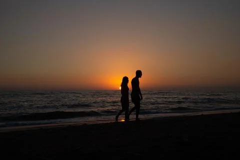 Two people walking at sunset Stock Photos
