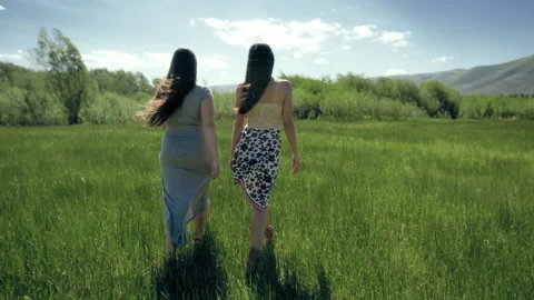 Two people walking through green fields on a sunny day in the hills Stock Footage 310199306