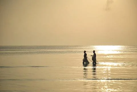 Two people walking through shallow sea water 库存照片
