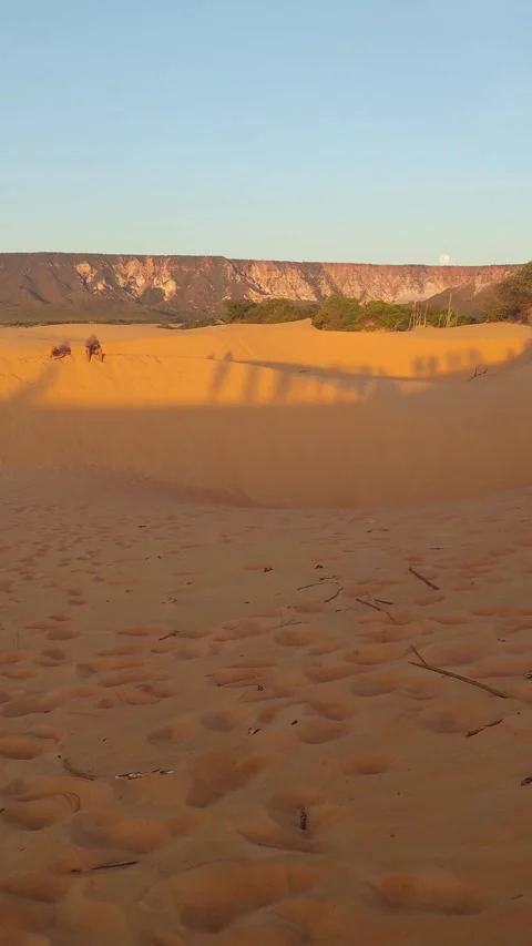 Two people watching the sunset from a sand dune in the desert with moon. Stock Footage 312898141