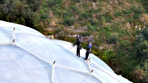 Two people working on the outside dome surface of a biome at the Eden Project. Stock-Footage 287933437