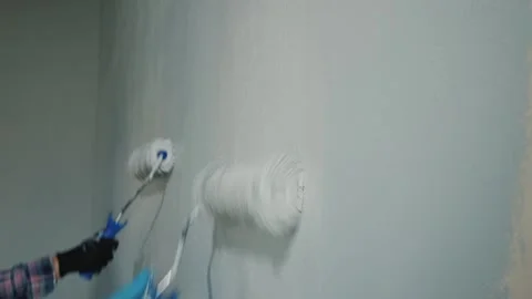 Two people working together to paint a wall with paint rollers, applying li.. Stock Footage 334835270