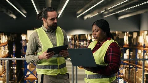 Two people working together on parcel tracking in industrial warehouse Stock Photos