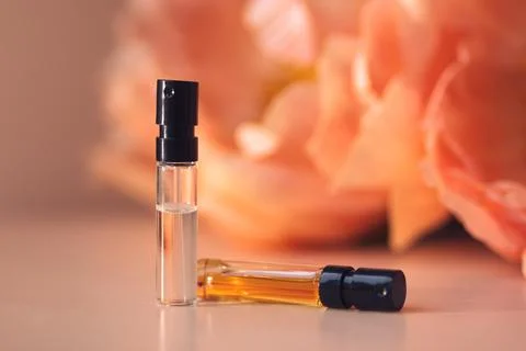 Two perfume samples with aroma water against peonies in soft focus. Face serum Stock Photos