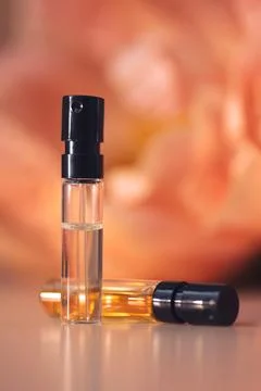 Two perfume samples with aroma water against peonies in soft focus. Face serum Stock Photos