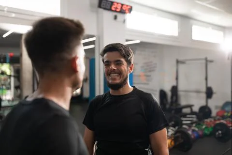 Two personal trainers smiling at each other at the gym Stock Photos