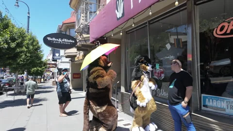 Two persons in dog suits holding a Pride parasol doing promo work. SF, USA. 스톡 동영상 282189406