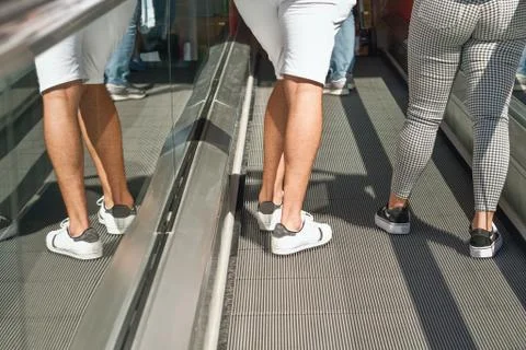 Two persons drive up an escalator, only the legs are visible, Stock Photos