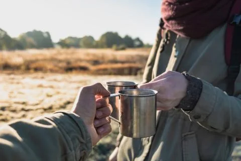 Two persons enjoying hot drinks at riverband in the morning.  Stock Photos