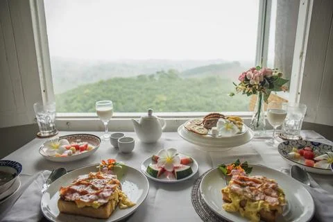 Two persons lunch at open window overlooking tropical rainforest, dining table Foto stock