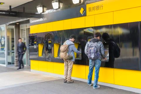Two persons using the ATMs outside the bank Photos
