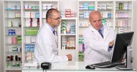 Two Pharmacist Colleague Talking About Medicine Stock Inside a Pharmacy Stock Footage 109120814