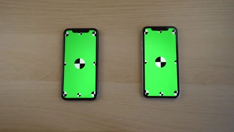 Two phones with a chromakey screen on the table. green screen phone replacement Stock Footage 246629869