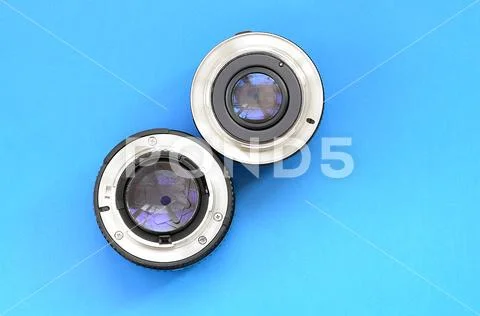 Two photographic lenses lie on a bright blue background. Space for text Stock Photos