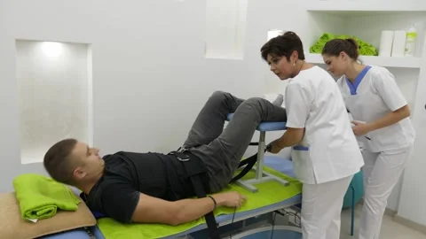 Two physiotherapists preparing a patient for the back stretching therapy 스톡 동영상 275826057