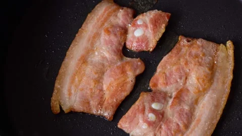 Two pieces of bacon are cooked in a pan Video stock 137226899