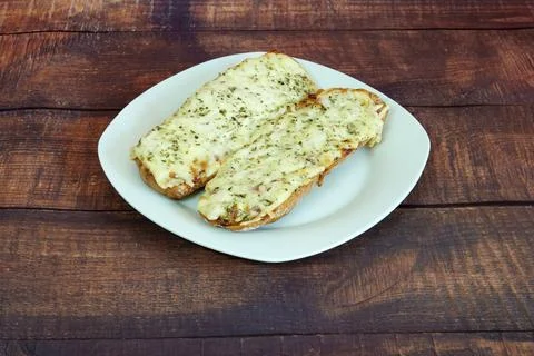 Two pieces of bread with cheese on top of a plate Stock Photos