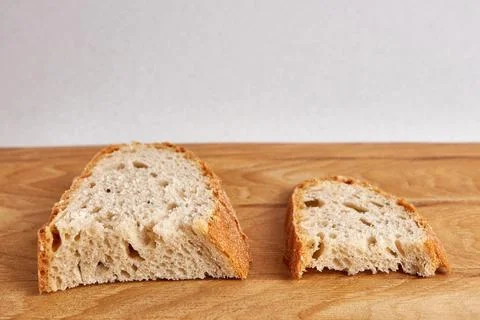 Two pieces of bread, a larger and a smaller piece on a wooden table. Food crisis Stock Photos