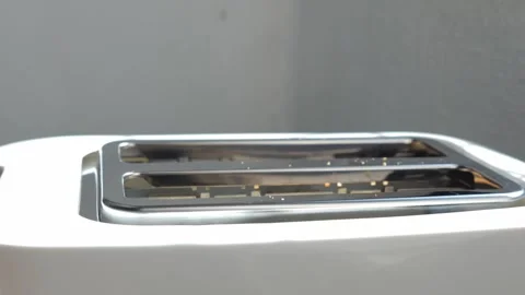 Two pieces of bread toasting in a modern white appliance until they become Stock Footage 329757598