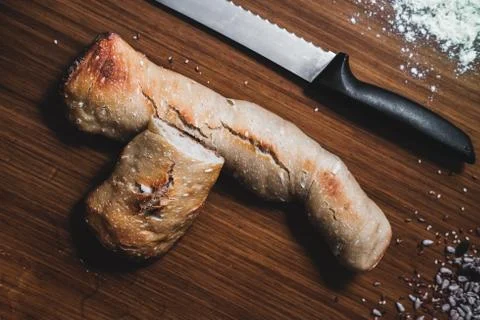 Two pieces of bread, white flour, water, seeds and a knife on the table Stock Photos