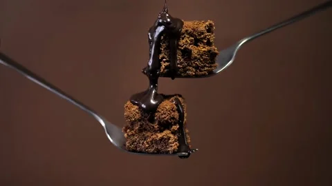 Two pieces of chocolate dessert on forks are poured with chocolate sauce Stock Footage 236839742