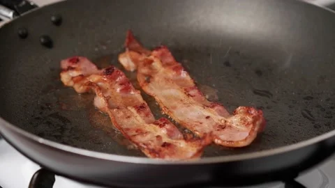 Two pieces of fried bacon in a hot frying pan. Ready to eat. Stock Footage 170915336