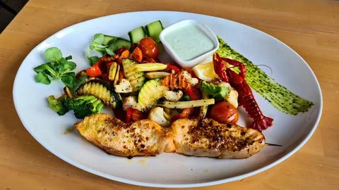 Two pieces of grilled fish with different vegetables on the dining table Stock-Fotos