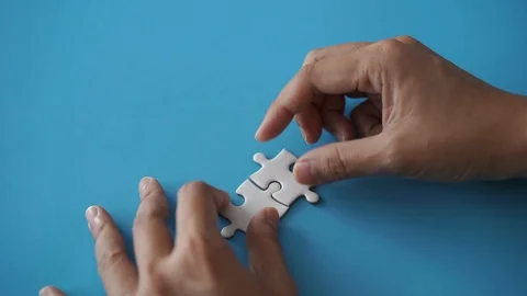 Two pieces of jigsaw put together by hand with copy space on left Stock Footage 120931816
