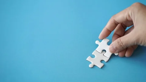 Two pieces of jigsaw put together by hand with copy space on left Stock Footage 120931824