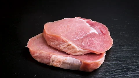 Two pieces of raw meat falling on black stone in slow motion Stock Footage 231989546