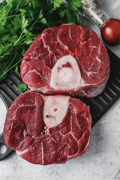 Two pieces of raw osabuko beef shank lie on a smooth black cutting board su.. Stock Photos