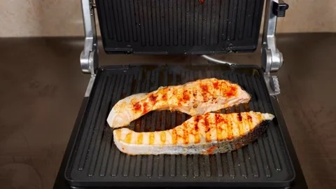 Two pieces salmon fish are cooking on the electric grill Stock Footage 143567694