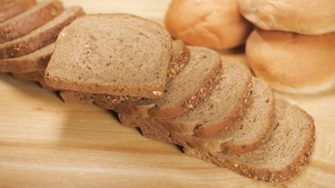 Two pieces of soft multi-grain bread dropping on a stack of bread ready for b... Stock Footage 197738427