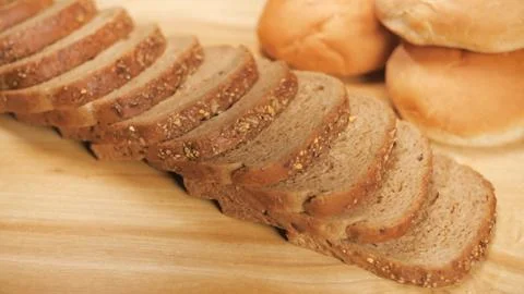 Two pieces of soft multi-grain bread dropping on a stack of bread ready for b... Stock Photos