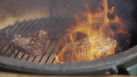 Two pieces of steak are cooking on a grill, with one piece being slightly burnt Stock-Footage 301629989