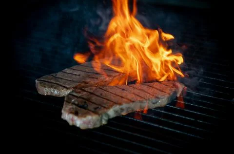 Two pieces of Striploin beef tips on getting grilled on a barbeque grill.GRIL Stock Photos