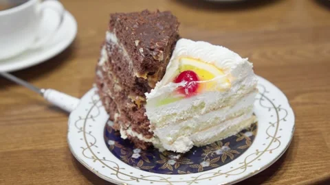 Two pieces of sweet cake, black and white, on plate on dining table. Видео 254769192
