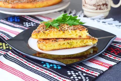 Two pieces of white cabbage pie with carrot on a black plate with cup of tea Stock Photos