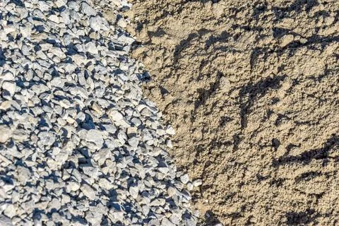 Two piles of building materials side by side one is rocks the other is sand Stock Photos