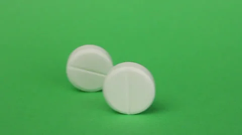 Two pills are rolling on a green background Видео 25877406