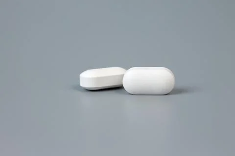 Two pills on a gray background. Stock Photos