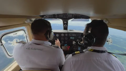 Two pilots operating small aircraft cockpit with instrument panel and headsets. Stock Footage 338361080
